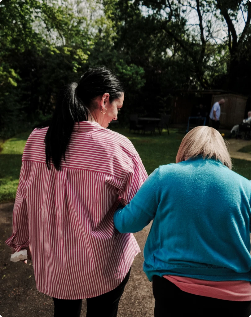 elderly woman with her arm wrapped around a nurse